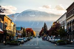 a city street with cars parked on both sides and mountains in the backgroud