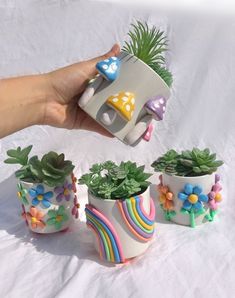 a hand holding a cup with some plants in it next to other potted plants