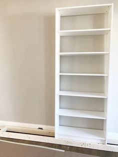 an empty white book shelf in the corner of a room with no one on it