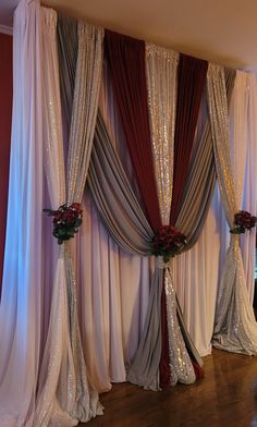 a room with curtains and flowers on the floor in front of a wall that is decorated with sequins