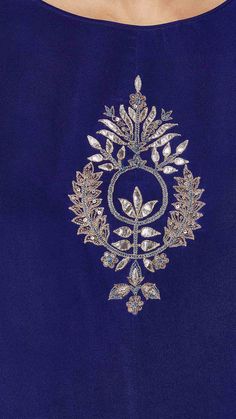 the back of a blue dress with an embroidered design on it, and silver details