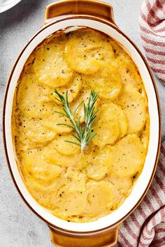 a bowl filled with potatoes and garnished with a sprig of rosemary