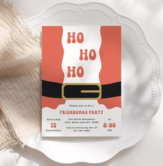 a white plate with a red and black christmas party card on it next to some yarn