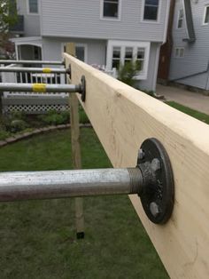 a close up of a metal handle on a wooden rail in front of a house