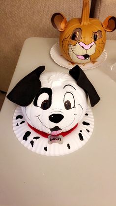 a paper plate with a dog and cat face on it sitting on a table next to a pumpkin