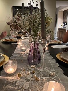 the table is set with candles, plates and glass vases on top of it