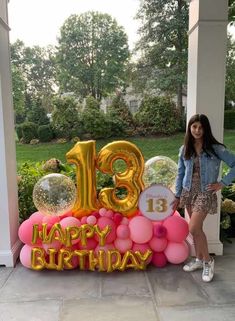 a woman standing in front of a large balloon number thirteen birthday sign with balloons on it