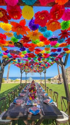 an outdoor dining area with colorful paper flowers on the ceiling and tables set for dinner