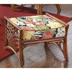 a chair with a floral upholstered seat and foot rest in front of a red rug