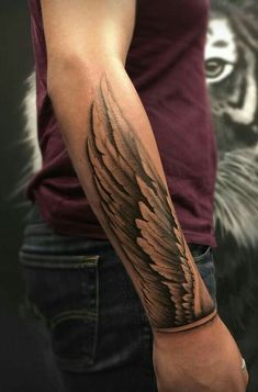 a man's arm with an angel wing tattoo on the left side of his arm