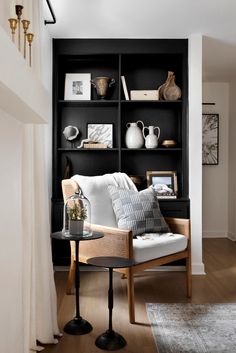 a living room with black shelving and white couches, coffee table and vases