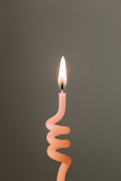 a lit candle with a spiral design on the side and a single light in the middle