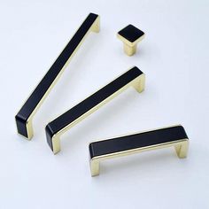 three black and gold door handles on a white surface, one has a square handle