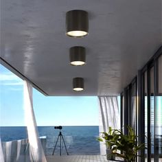 three lights are hanging from the ceiling in front of an open balcony overlooking the ocean