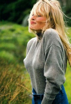 a woman with long blonde hair standing in the grass