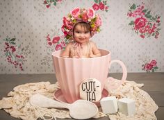 a baby sitting in a pink cup with a sign that says cute tea on it