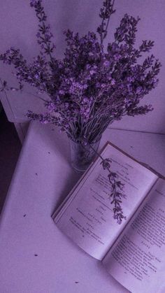 an open book sitting on top of a table next to a vase filled with flowers