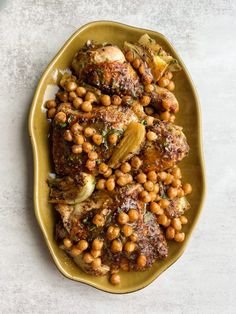 a yellow plate topped with meat covered in chickpeas and garbanzo beans