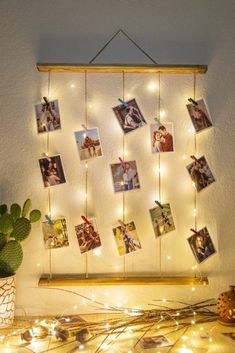 a wooden frame with pictures hanging from it and string lights on the wall behind it