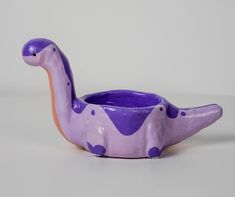 a purple ceramic bird shaped planter with spots on it's body and neck