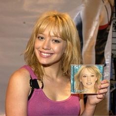 a woman holding up a cd in front of her face and smiling at the camera