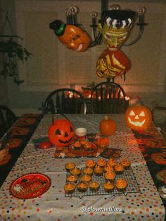 a table topped with lots of pumpkins and cupcakes