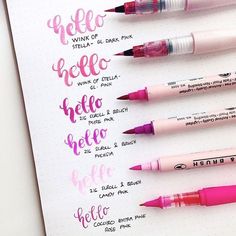 some pink pens are lined up on top of a white paper with the words hello written in cursive writing