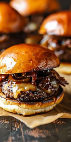 a cheeseburger is sitting on top of some brown paper with other burgers in the background