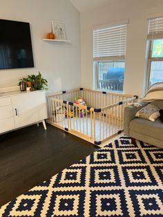 a baby crib in the corner of a room next to a couch and television