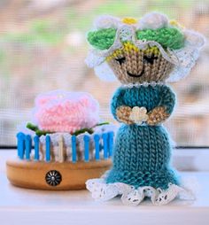 a knitted doll next to a birthday cake on a window sill in front of a window