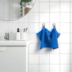 two blue towels are hanging on the wall next to a white sink and mirror in a bathroom