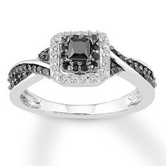 an engagement ring with black and white diamonds on the band, set in 18k white gold