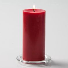 a red candle is sitting on a glass stand with a white background and the words quick candles written below it