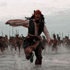 a man with dreadlocks is running through the water in front of other men