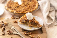 a slice of pecan pie on a plate with a fork next to the pie