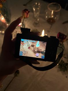 a person is holding up a camera to take a photo with candles in the background