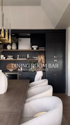 a dining room bar with white chairs and black cabinets