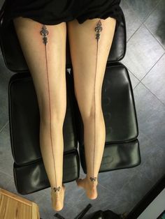 two legs with tattoos on them sitting on a chair