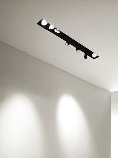 three spotlights are on the ceiling above a bed in a room with white walls