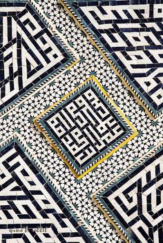 an intricate pattern with gold and blue accents on the side of a black tile wall