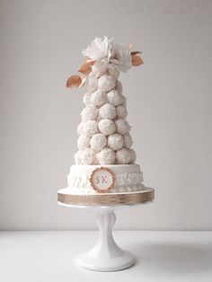 a three tiered cake with white frosting and pink flowers on top, sitting on a pedestal