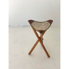 a small wooden chair with a leather seat on it's legs and a white wall in the background