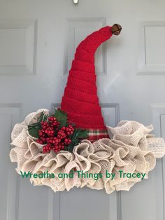 a red knitted christmas hat hanging on the front door with holly and berries in it