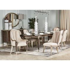 a dining room table with beige chairs and white vases on top of the table