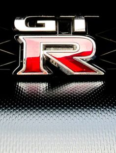 the emblem on top of a car that is red and black with silver letters reading gtr