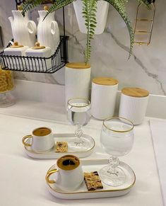 there are three cups and two plates on the table with gold trimmings around them