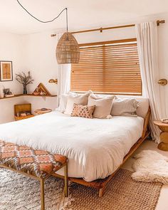 a bedroom with a bed, window and rugs on the floor in front of it