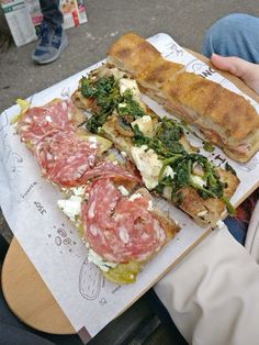 a person is holding a sandwich with meat and vegetables on it in front of them