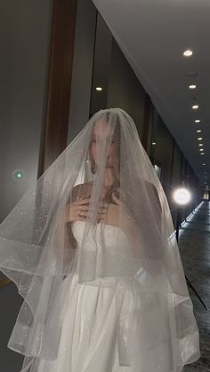 a woman in a white wedding dress and veil is posing for the camera with her hands on her chest