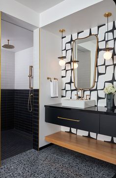 a modern bathroom with black and white tiles on the wall, gold trim around the sink